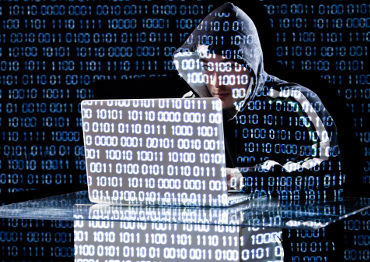 Hacker typing on a laptop with binary code in background