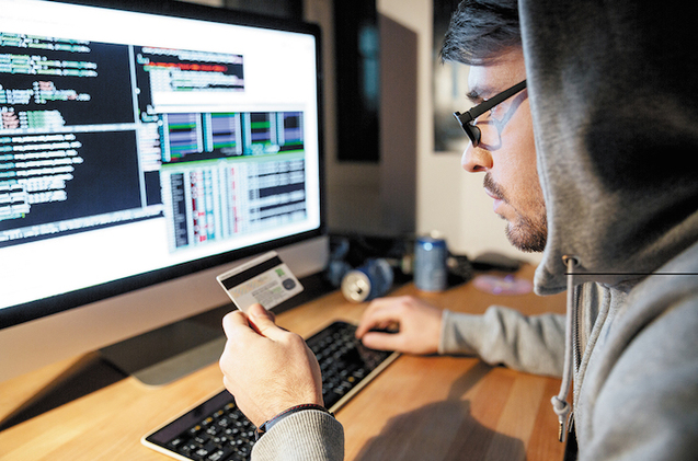 Concentrated hacker in glasses stealing money from diferent credit cards