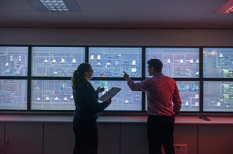 Tutor and student in front of monitors in ship’s engine room simulator