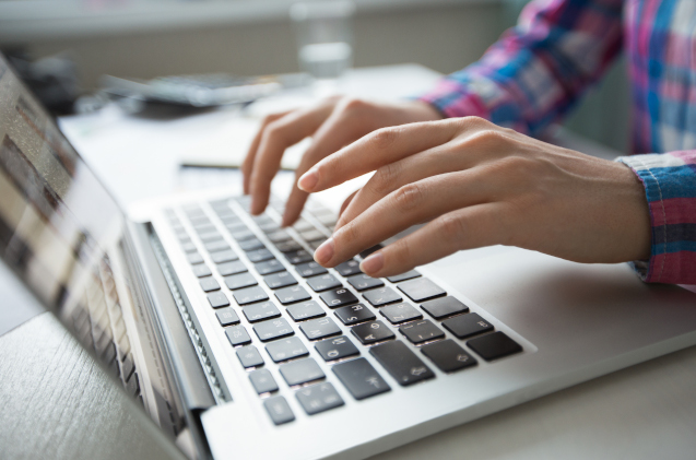 Cropped View of Hands Typing on Laptop
